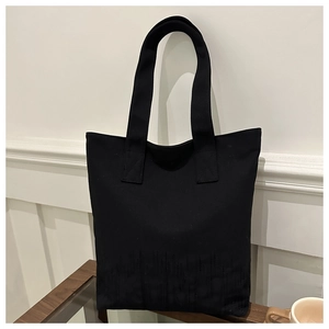 Close-up of minimalist black canvas tote bag showing dark textured line embroidery detail