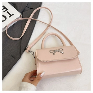 Detail of light pink mini square bag with silver metal bow and polished PU leather texture