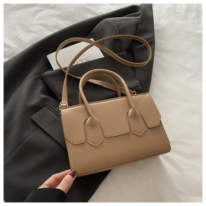 Detail of khaki leather crossbody bag with shield stitching on grey blazer background