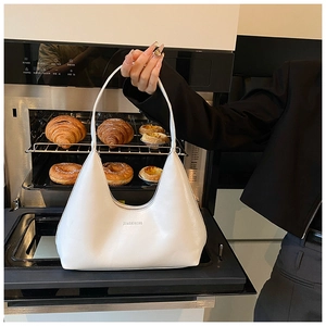 Dettaglio della borsa a mezzaluna beige in ecopelle con logo in un ambiente moderno