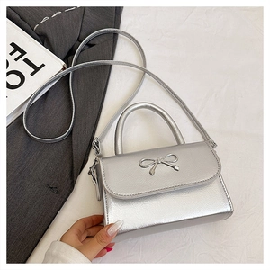Detail of silver metallic bow buckle and PU leather texture on the stylish mini bag