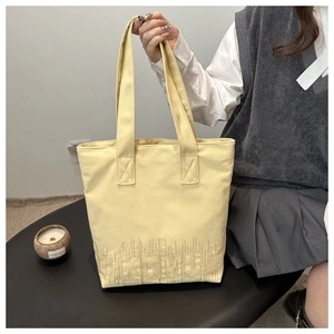 Detailed view of yellow canvas tote bag with KTMU embroidery and large capacity strap