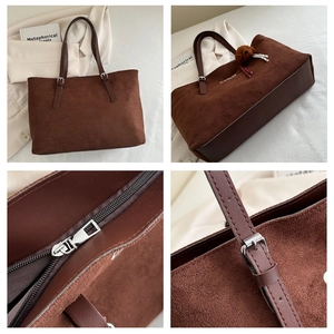 Detail of brown suede tote bag featuring adjustable strap, zipper, and bear charm