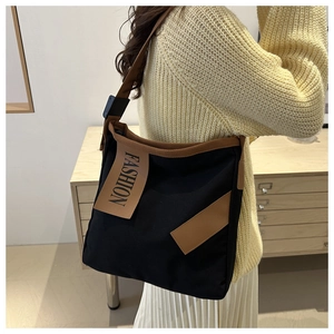 Detail view of canvas tote showing adjustable buckle and brown fashion label patch