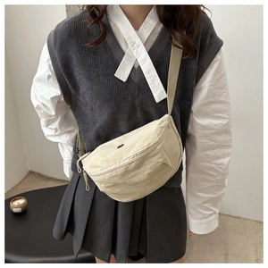 Adjustable beige canvas crescent crossbody bag worn by a model in a minimal casual style