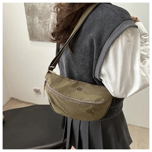 Olive green nylon crescent bag worn by model showing adjustable strap and sleek texture