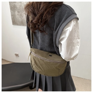 Rear view of an olive green nylon crossbody bag with adjustable straps and zipper details