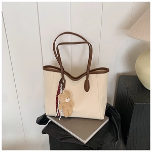Détail du sac cabas crème en cuir grainé avec anses marron et charme d'ours en peluche