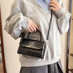 Chic black bow handbag with glossy cracked leather texture and silver metallic hardware
