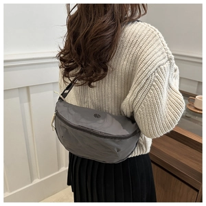 Detailed back view of a grey nylon crescent crossbody bag worn over a beige sweater
