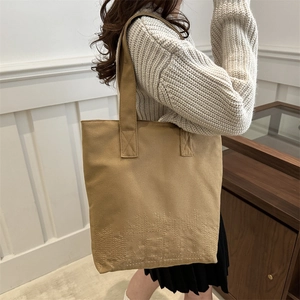 Khaki canvas tote bag with textured embroidery and wide shoulder straps for daily commute