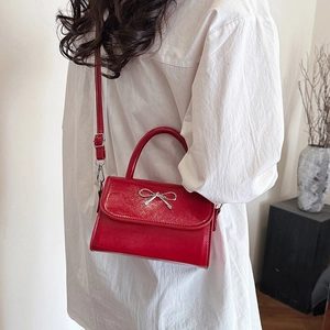 Red patent leather crossbody bag with silver bow accent and versatile shoulder strap