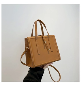 Detailed view of a brown structured tote bag with top handles and adjustable shoulder strap