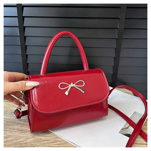 Vue détaillée d'un sac carré en cuir verni rouge avec nœud métallique argenté