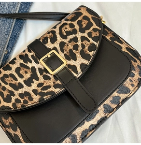 Dettaglio della patta leopardata con cinturino in pelle nera e fibbia in metallo