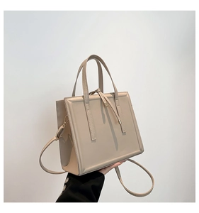 Detail of beige structured tote bag with vertical stitching and gold buckle tassel