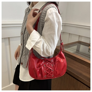 Close-up of red PU leather underarm bag with corset-style lace-up silver eyelet details