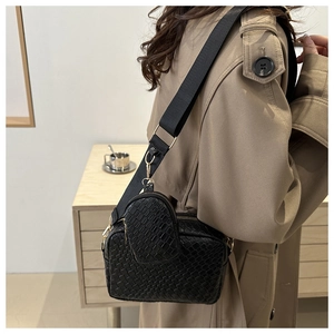 Dettaglio borsa a tracolla nera intrecciata con tracolla larga e mini pochette tonda