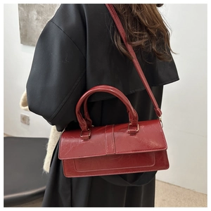 Deep red vintage oil-wax leather baguette bag shown as a crossbody detail on model