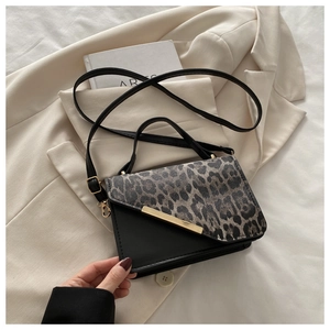 Détail d'un sac à main léopard avec boucle dorée sur un blazer beige chic