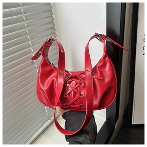 Close-up of red balletcore half-moon bag featuring criss-cross lace-up design and silver hardware