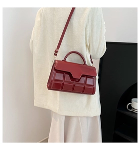 Detail of red quilted square crossbody bag with gold hardware and top handle strap