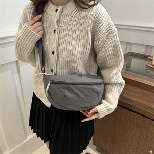 Gray nylon half-moon crossbody bag with adjustable strap worn by model in casual style