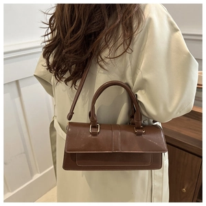 Model wearing dark brown vintage baguette bag with flap closure and adjustable strap