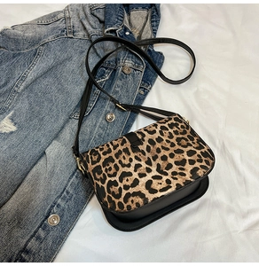 Dettaglio borsa vintage leopardata con cinturini in pelle nera e finiture dorate