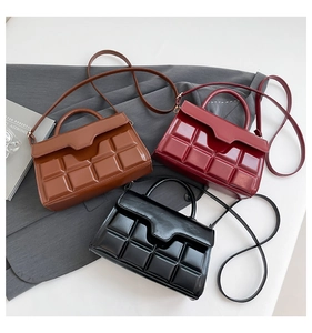 Close-up of geometric quilted crossbody bags in brown, burgundy, and black glossy leather