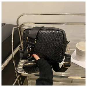 Dettaglio della borsa in pelle intrecciata nera con tracolla larga e mini pouch tonda