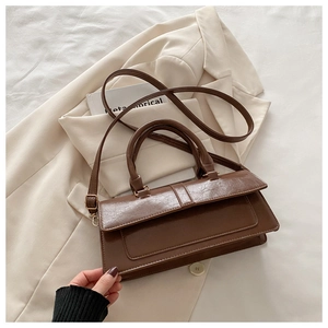 Close-up of deep brown textured faux leather bag with vintage metal flap closure