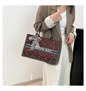 Détail du sac cabas léopard avec ruban et bandoulière logo porté par le mannequin