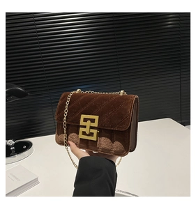 Détail du sac bandoulière en velours marron avec surpiqûres et fermoir doré carré