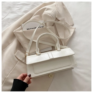 Detail of cream white rectangular handbag on beige blazer with golden hardware