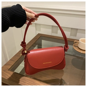 Close-up of deep red leather handbag featuring knotted handle and gold text detail