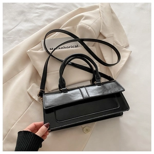 Detail view of the sleek black faux leather texture and elegant handles of the handbag