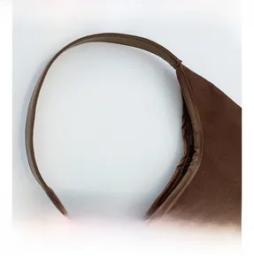 Detail of brown suede shoulder bag showing reinforced stitching on durable handles