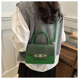 Detailed view of a green crossbody bag with woven texture lid and golden metal lock