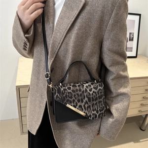 Petit sac à main léopard contrasté avec barre dorée porté en bandoulière par un modèle