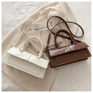 Close-up of white and brown minimalist leather handbags with elegant gold metal buckles