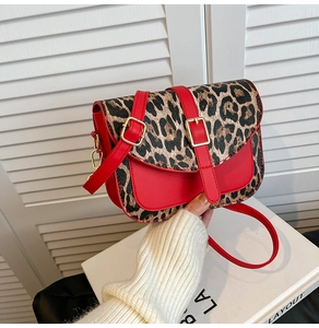 Dettaglio della borsa a spalla in pelle rossa con patta leopardata e fibbie in metallo oro