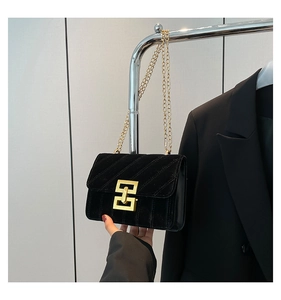 Détail du sac à bandoulière en velours noir matelassé avec fermoir géométrique doré