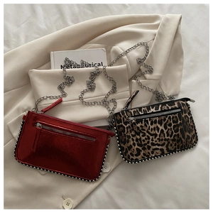 Detail of red metallic and leopard print crossbody bags with silver chain straps and studs