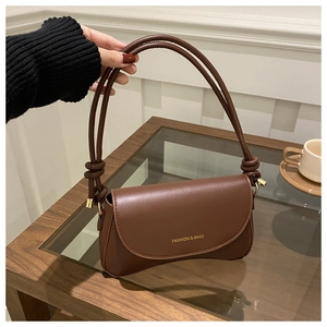 Close-up of brown faux leather shoulder bag with gold logo and knotted strap detail