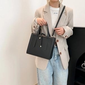 Elegant black leather tote bag with drawstrings shown on a model in a minimalist style