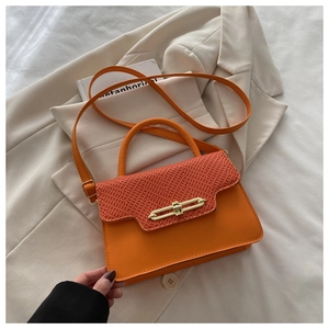 Top view of an orange leather crossbody bag with V-weave texture and golden lock on a suit