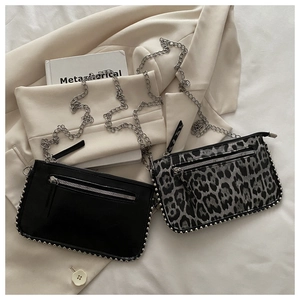 Chic small crossbody bag with silver studs and metal chain on a beige blazer
