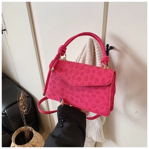Détail du sac à main rose avec gaufrage floral, poignée nouée et finitions dorées