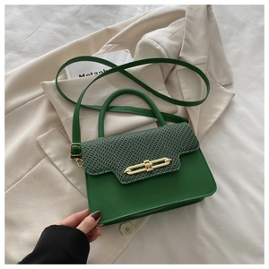 Detail of emerald green quilted crossbody bag with golden matte bar lock on a blazer